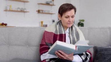 Evde kanepede otururken kıdemli bir kadın kitap okuyor. Kendini karantinaya almış bir kadının emeklilik hayatı