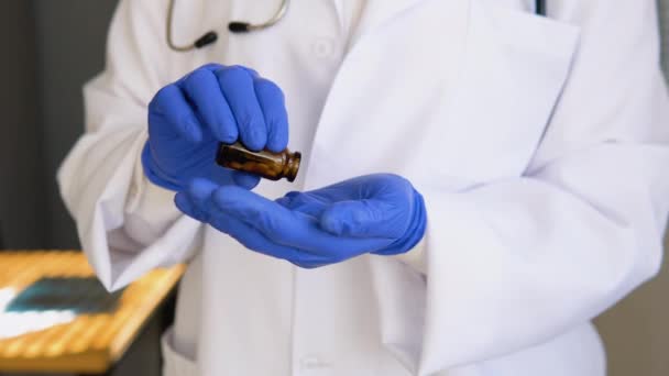 Senior vrouwelijke arts in witte jas neemt pillen uit een pot. Close-up zicht van de handen — Stockvideo