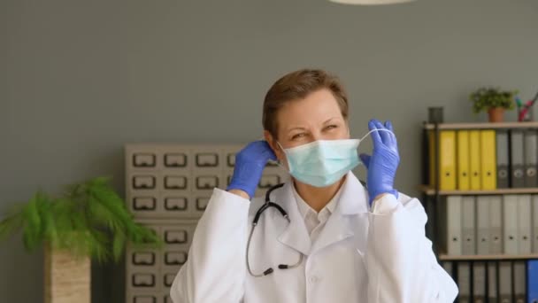 Positieve vrouwelijke arts verwijdert een medisch masker in de kliniek. Einde quarantaine. Stop het virus — Stockvideo