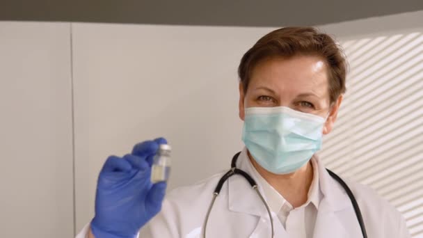 A rangidős doktornő egy ampullát tart egy vakcinával a kezében. Védőoltás fogalma — Stock videók