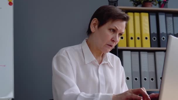 Kıdemli kadın dizüstü bilgisayarın arkasında çalışıyor. Uzak çalışma kavramı — Stok video