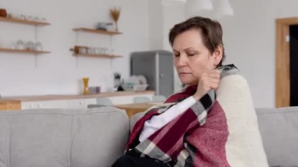 Η ηλικιωμένη γυναίκα βήχει ενώ κάθεται στον καναπέ. Εποχιακές ασθένειες, βήχας, κρύο — Αρχείο Βίντεο