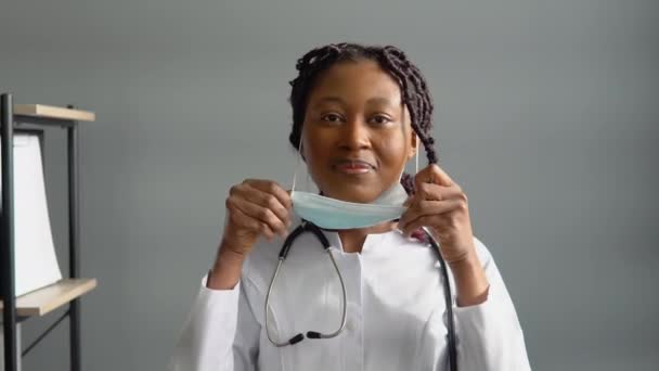 Mladá africká americká lékařka si nasadí ochrannou modrou masku. Ochrana proti virům — Stock video