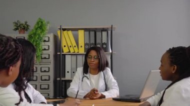 Bir grup Afrikalı Amerikalı kadın doktor masada bir şey tartışıyor.