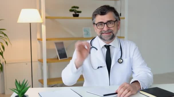 Positieve senior Kaukasische mannelijke arts die externe klant online adviseert via videoconferentie. Webcam weergave — Stockvideo