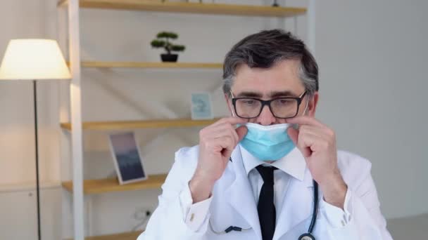 Le médecin principal met un masque bleu protecteur. Protection contre les virus — Video