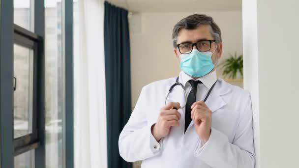 Portrait d'un médecin chevronné en costume blanc et masque de protection — Video