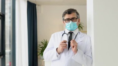 Beyaz takım elbiseli ve koruyucu maskeli kıdemli bir doktorun portresi. Virüs Koruma