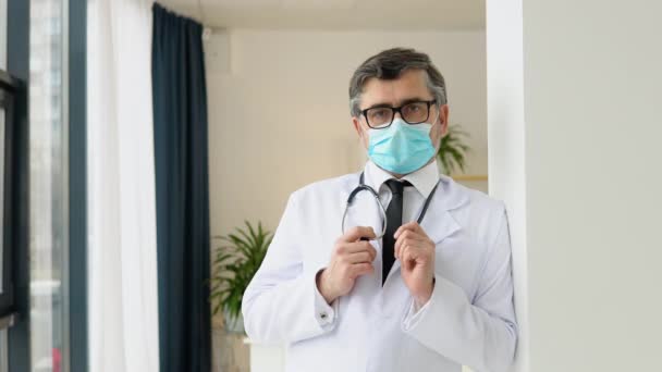 Портрет старшего врача в белом костюме и защитной маске. Защита вирусов — стоковое видео