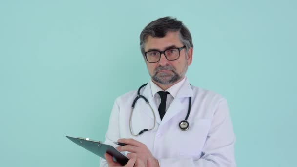 Senior läkare skriva information i medicinsk registrering journal på blå bakgrund — Stockvideo
