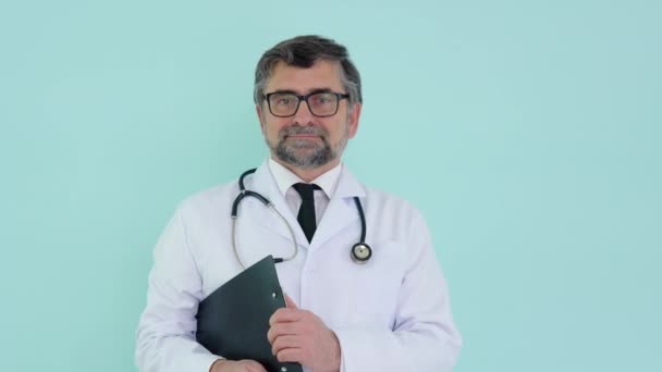 Stetoskop ve kayıt günlüğüyle beyaz takım elbiseli bir doktorun portresi. — Stok video