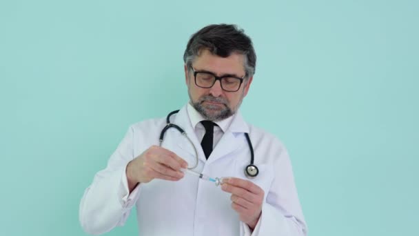 Läkaren håller en spruta och en vaccinflaska på sjukhuset på blå bakgrund. Hälsa och medicinska begrepp — Stockvideo