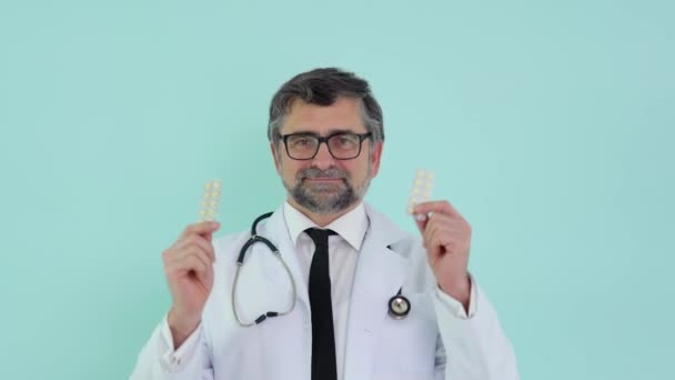 Consultor de farmacêutico médico sênior mostrando dois pacotes de pílulas e sorrindo na câmera. Conceito de medicina e saúde, educação médica, setor farmacêutico — Vídeo de Stock