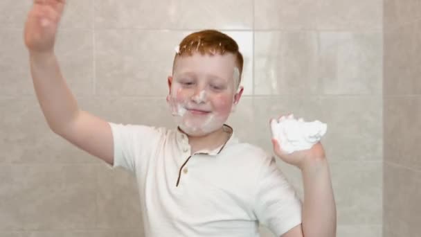 Αστείο αγόρι που χορεύει στο μπάνιο με κρέμα ξυρίσματος στο πρόσωπό του. — Αρχείο Βίντεο