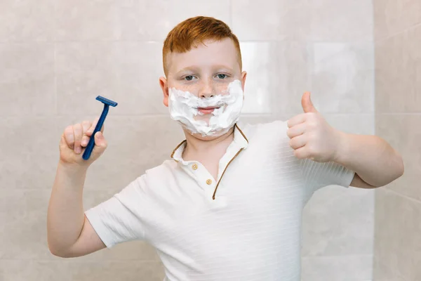 Anak lucu di kamar mandi dengan krim cukur di wajahnya dan cukur cukur — Stok Foto