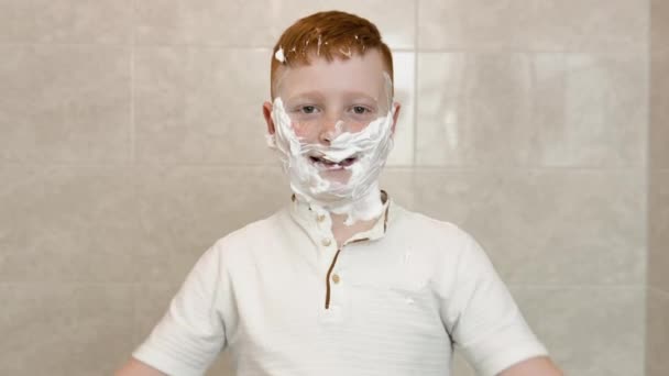 Garoto engraçado no banho com creme de barbear em seu rosto mostra um sinal de consentimento com o polegar para cima — Vídeo de Stock