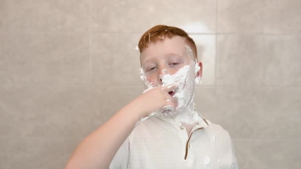 Divertente ragazzo nel bagno si spalma il viso con la crema da barba mostra un segno di consenso con il pollice in su — Video Stock