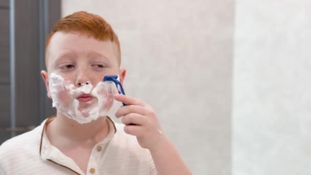 Мальчик бреет лицо в ванной. — стоковое видео