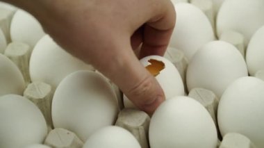 El kırık yumurtayı platformdaki tüm yumurtaya çeviriyor. Yakın çekim. Bir sürü çiğ tavuk yumurtası.