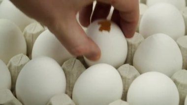 El kırık yumurtayı platformdaki tüm yumurtaya çeviriyor. Yakın çekim. Bir sürü çiğ tavuk yumurtası.