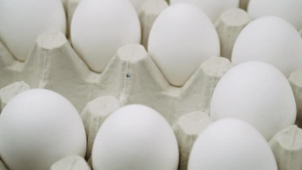 La mano que pone muchos huevos blancos y un huevo de oro en la plataforma - de cerca. Un montón de huevos crudos de pollo fresco — Vídeos de Stock