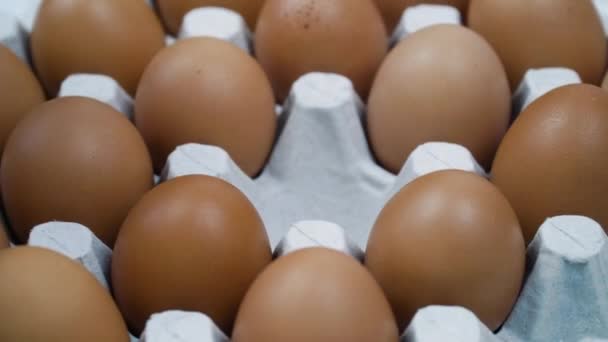 La mano cambia el huevo roto a todo el huevo de oro en la plataforma - de cerca. Un montón de huevos crudos de pollo fresco — Vídeo de stock