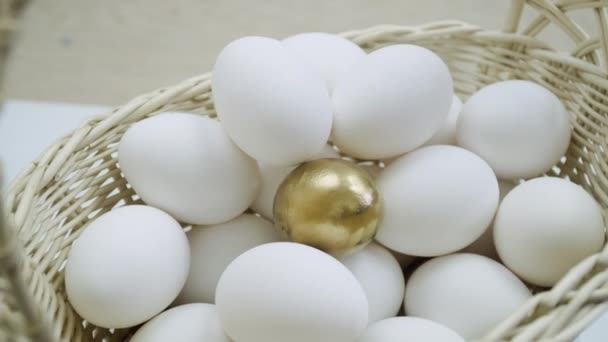 Сырые белые яйца и одинокое золотое яйцо в корзине. Белые куриные яйца в свою очередь вид сверху — стоковое видео