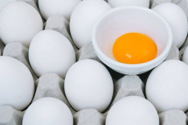 Beyaz çiğ tavuk yumurtası ve kırık kahverengi yumurta tepsinin üstünde.