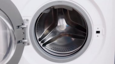 Erkek el, tıbbi maskeleri çamaşır makinesine koyar. Çamaşır makinesi yükleniyor