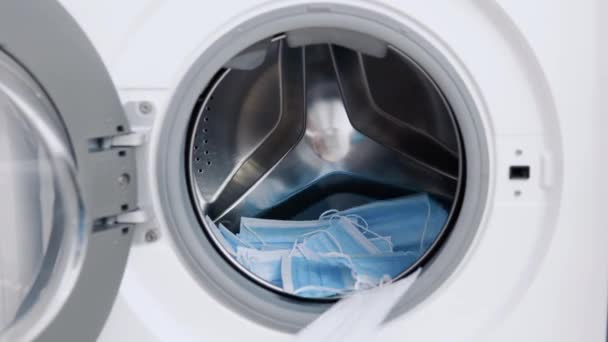 Медичні маски ставлять у пральну машину. Завантаження пральної машини. прання — стокове відео