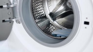 Erkek el, tıbbi maskeleri çamaşır makinesine koyar. Çamaşır makinesi yükleniyor. Çamaşır yıkama