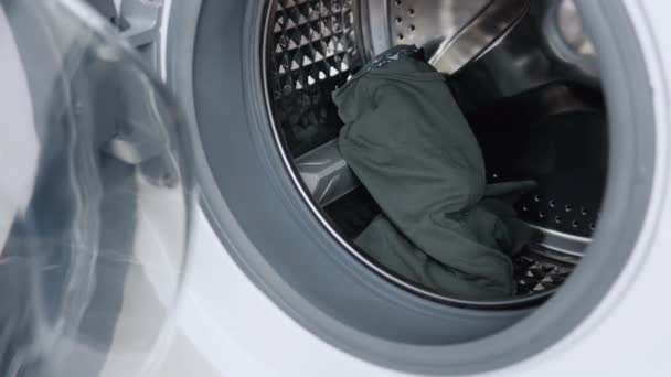 De mannelijke hand doet de kleren in de wasmachine en sluit de deur. Wasmachine laden — Stockvideo