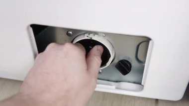 Erkek el kirli ve tıkanmış çamaşır makinesi pompa filtresini kaldırır. Evdeki ev aletlerini kendi elleriyle tamir ediyorlar. Tamirci çamaşır makinesini tamir eder.