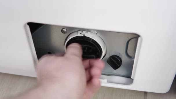 La mano masculina elimina el filtro de bomba de lavadora sucia y obstruida. Servicios de reparación de electrodomésticos en el hogar — Vídeo de stock