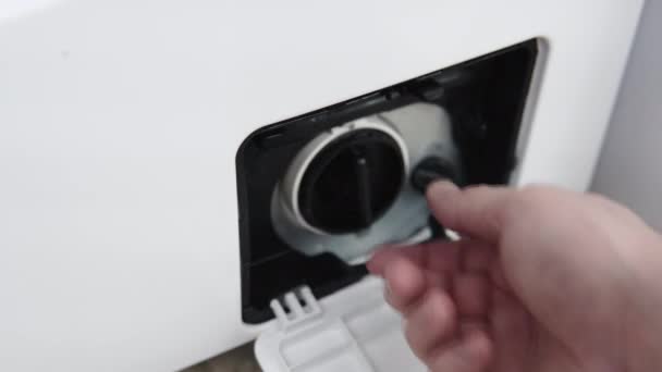 Männliche Hand entfernt verschmutzten und verstopften Pumpenfilter der Waschmaschine. Reparatur von Haushaltsgeräten zu Hause mit ihren eigenen Händen. der Reparateur repariert die Waschmaschine — Stockvideo