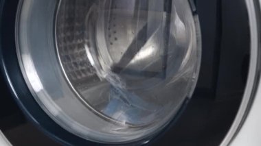 Çamaşır makinesi kirli tıbbi maskeleri yıkar. Dönen davul çamaşır makinesinin videosunu kapat