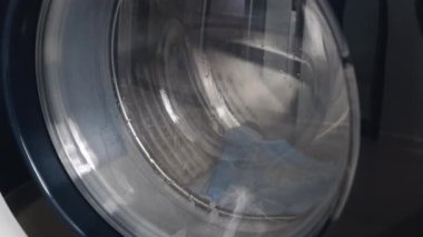 Çamaşır makinesi kirli tıbbi maskeleri yıkar. Dönen davul çamaşır makinesinin videosunu kapat