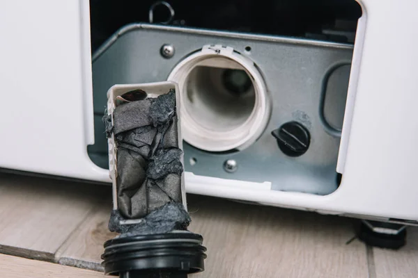 Erkek el kirli ve tıkanmış çamaşır makinesi pompa filtresini kaldırır. Ev aletlerinin onarımı için hizmetler