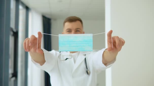 남자 의사가 자기 앞에 보호용푸른 마스크를 들고 있다. 바이러스의 보호 — 비디오