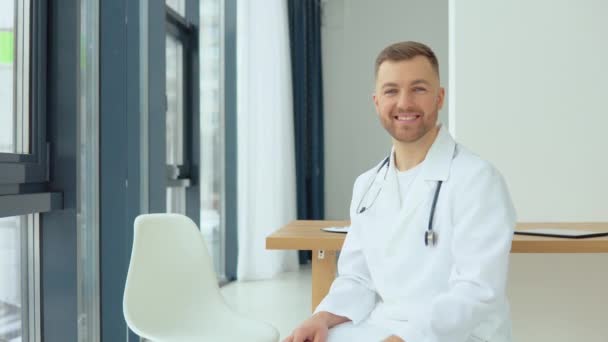 Ein freundlicher Arzt lädt einen Patienten zu einem Beratungsgespräch ein — Stockvideo