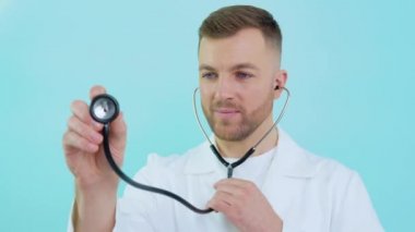 Mavi arka planda beyaz önlüklü steteskoplu bir erkek doktor.