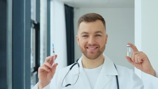 De dokter heeft een ampul met een vaccin en een spuit in zijn handen. Vaccin COVID-19 — Stockvideo