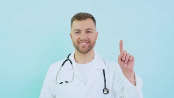 Docteur avec stéthoscope en manteau blanc lève son index jusqu'au niveau du visage sur un fond bleu — Video