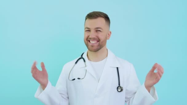 Wesoły udany lekarz z stetoskopem w białym płaszczu na niebieskim tle — Wideo stockowe