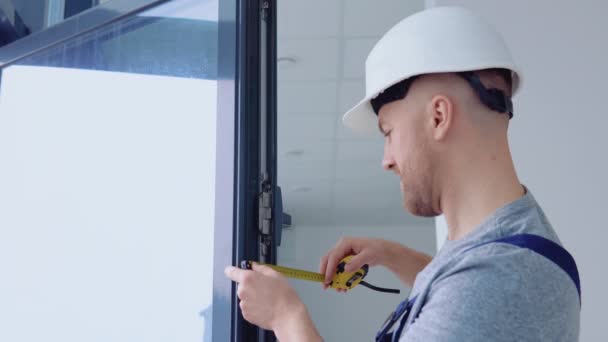 Instalador de ventanas mide las dimensiones del marco de la ventana con una cinta métrica — Vídeos de Stock