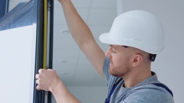 Fensterbauer misst die Maße des Fensterrahmens mit einem Meterband — Stockvideo