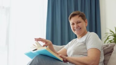 Rahat bir son sınıf öğrencisi olarak kanepede oturup evde kitap okuyorum. Modern konforlu dairede olgun bir kadının boş aktivitesi. Sıradan bir yaşlılık ve buruşuk cilt bakımı.