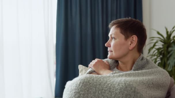 Smutná starší dospělá žena sedí doma na gauči sama. Zdravý šťastný senior žena babička cítí spokojen pózování pro zblízka v obývacím pokoji — Stock video