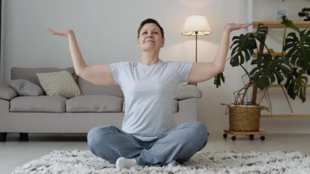 Senior woman doing meditation exercise stretching sports yoga. Bright Room at Home — Vídeos de Stock