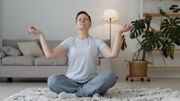 Senior kvinna som mediterar och stretchar sportyoga. Mogen frisk kvinna träning hemma, motion, passform, gör yoga, hem fitness koncept — Stockvideo